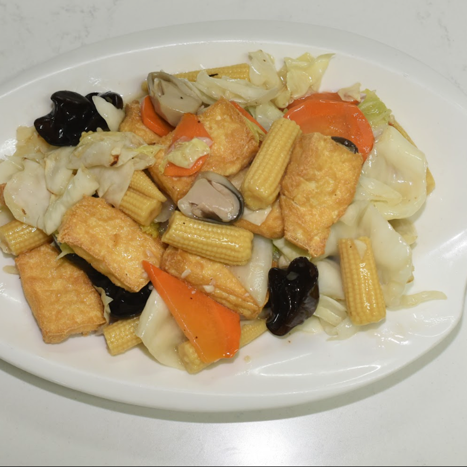 Plate of stir-fried mixed vegetables with baby corn, cabbage, carrots, mushrooms, black fungus, and golden tofu pieces.